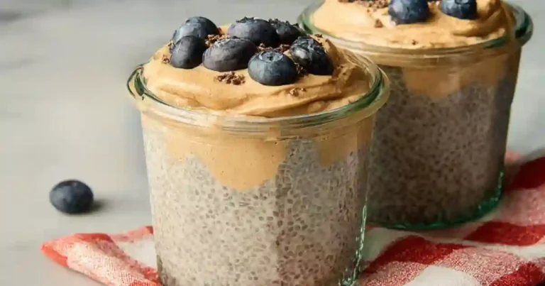 Peanut butter chia pudding in a clear jar with fresh berries and cacao nibs on top