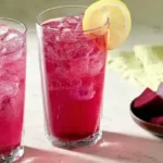 A glass of bright pink beet lemonade, easily made at home using a blender.