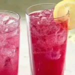 A glass of bright pink beet lemonade, easily made at home using a blender.